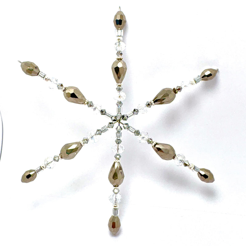 A snowflake-shaped beaded ornament featuring metallic champagne-gold faceted beads and clear crystal accents, displayed on a clean white background.