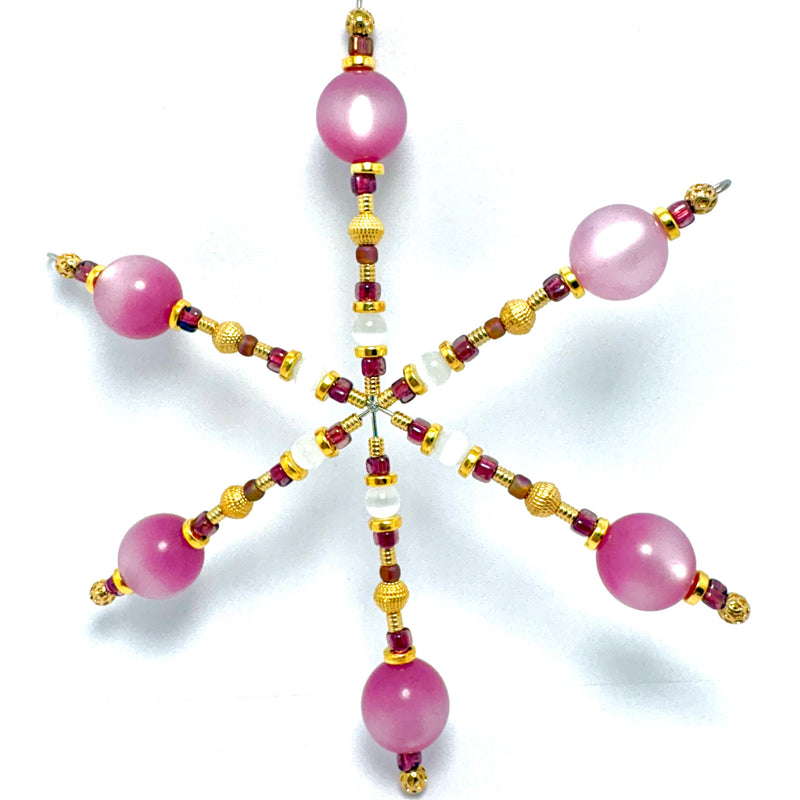 A six-pointed star-shaped beaded ornament or pendant featuring large pink round beads, gold-toned textured beads, and small dark red and white beads, displayed on a clean white background.